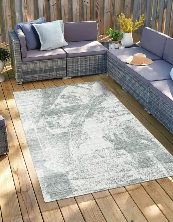 Abstract gray and white rug on a wooden deck surrounded by a large gray outdoor sectional.