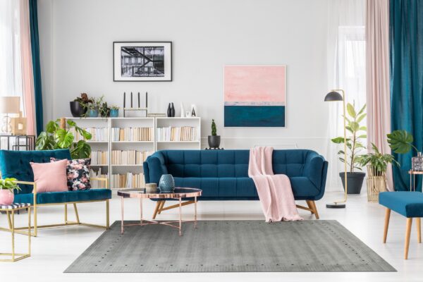 Gray rug with subtle texture and dotted border under a rose gold table and blue velvet sofa.