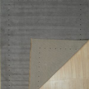 Smooth gray rug with a dotted pattern border folded over light wood plank flooring.