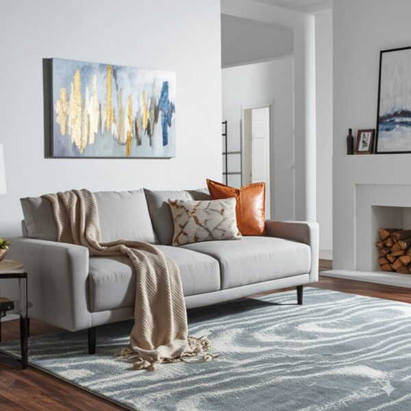A blue and white rug with a swirling abstract pattern grounds a grey sofa on a dark wood floor.