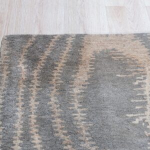 A plush gray rug with abstract beige motifs sits next to light blonde hardwood flooring.