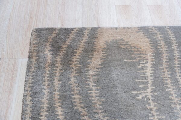 A plush gray rug with abstract beige motifs sits next to light blonde hardwood flooring.