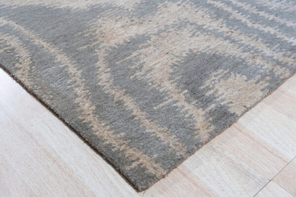 High-pile gray and beige abstract rug displaying a distressed pattern on pale wood flooring.