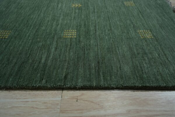 Textured deep green rug with scattered yellow geometric patterns resting on light wood plank flooring.