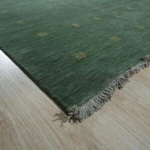 A dark green rug with small gold accent patterns and gray fringe rests on light wood flooring.