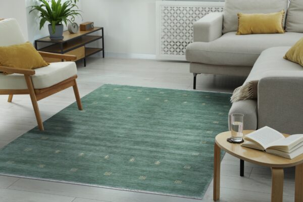 Striated teal rug with scattered small light motifs anchors a bright living room with neutral furniture.