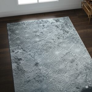 A textured gray rug with light radial patterns lies on dark wood flooring near a window.