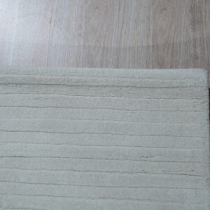 Off-white ribbed rug texture visible next to pale wood-look plank flooring.