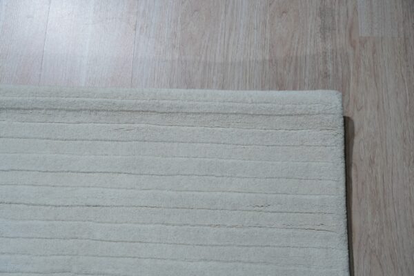 Off-white ribbed rug texture visible next to pale wood-look plank flooring.