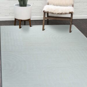 Pale gray low-pile rug with carved geometric arches rests on dark wood near a fur-covered chair.