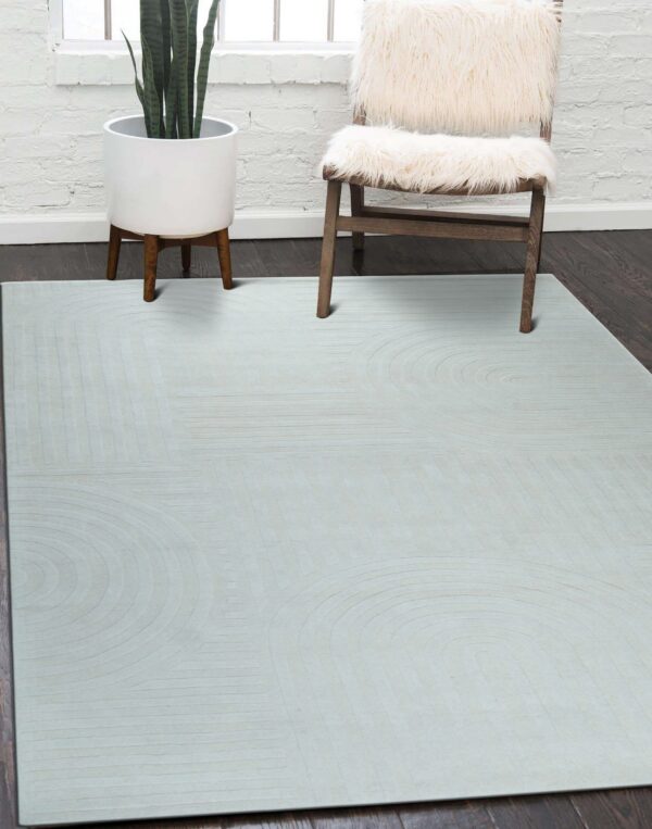 Pale gray low-pile rug with carved geometric arches rests on dark wood near a fur-covered chair.