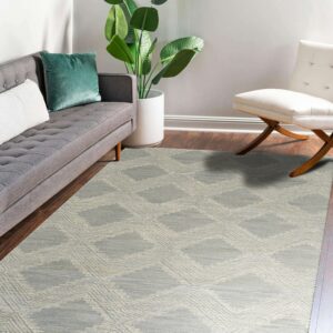 Geometric gray and cream rug on dark wood planks, flanked by a gray couch and white accent chair.