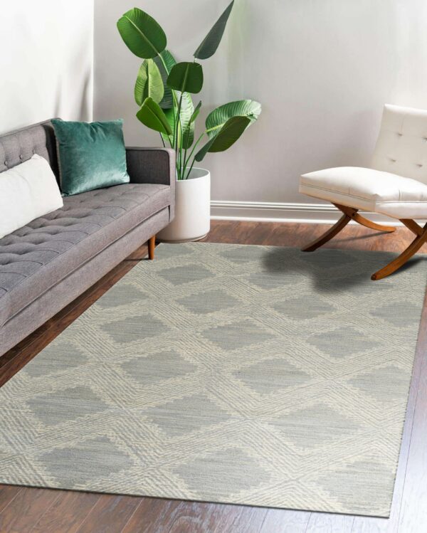 Geometric gray and cream rug on dark wood planks, flanked by a gray couch and white accent chair.