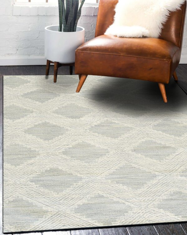 Textured cream and gray rug with diamond shapes displayed under a brown leather chair.