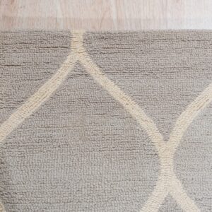 Textured loop pile rug in griege and cream featuring a bold geometric pattern on light wood flooring.