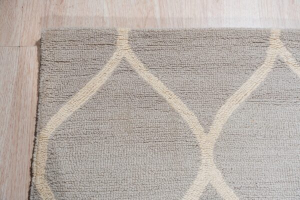 Textured loop pile rug in griege and cream featuring a bold geometric pattern on light wood flooring.