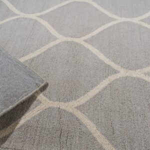Light gray rug with a beige geometric pattern, partially rolled back on light wood flooring.