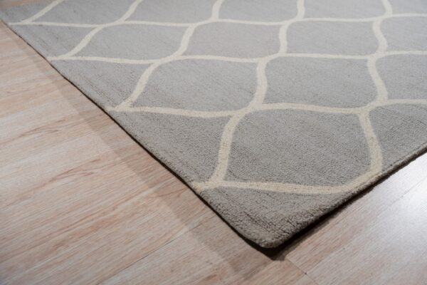 A textured gray rug featuring an off-white geometric pattern rests on light wood planks.