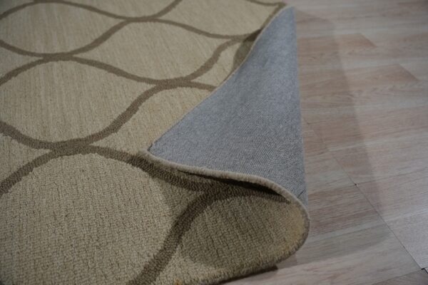 Textured beige and taupe rug with an interlocking pattern partially covers light wood flooring.
