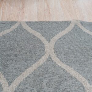 Textured blue and cream rug with an intersecting trellis pattern rests on light hardwood flooring.