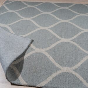 Light blue textured rug featuring an off-white geometric ogee pattern on a light wood floor.