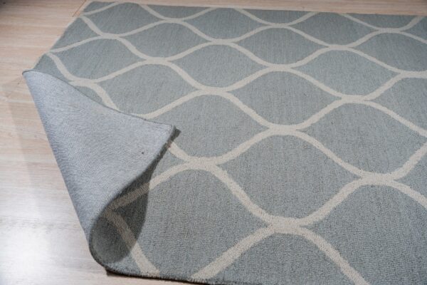 Light blue textured rug featuring an off-white geometric ogee pattern on a light wood floor.
