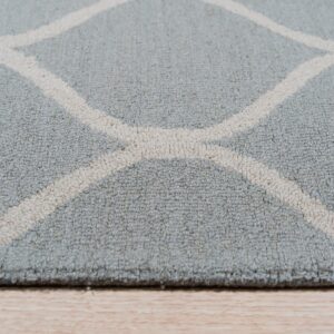 Low-angle detail of a textured blue-gray rug featuring a cream geometric trellis on wood floor.