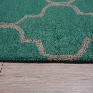 Textured green rug with a beige trellis pattern borders light blonde wood flooring.