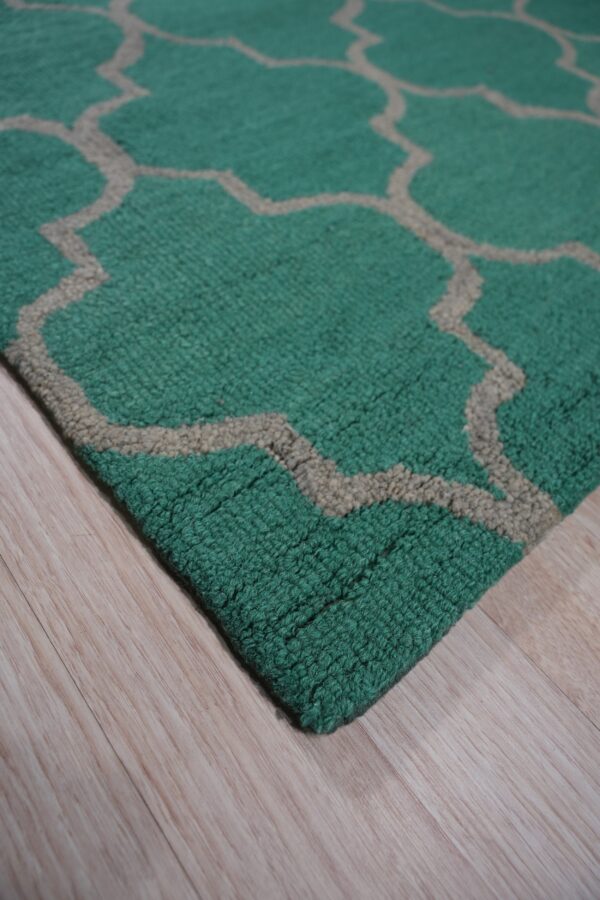 A chunky teal rug with a tan moroccan lattice pattern rests on light wood flooring.