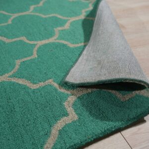Teal quatrefoil pattern rug lifted to show the textured pile and gray woven backing on light wood flooring.