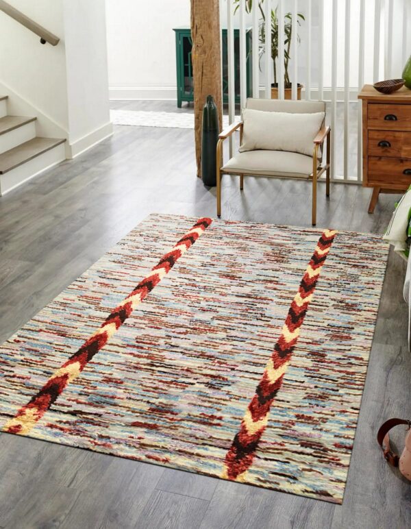 Textured rug with multicolor abstract stripes and diagonal chevron bands lies on glossy gray wood flooring.