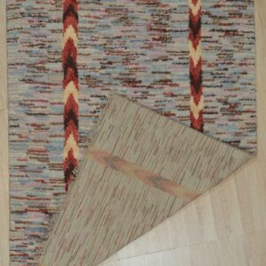 A shaggy blue and brown rug with chevron stripes is folded back on light wood plank flooring.