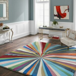 A rainbow-striped rug with a radiant sunburst pattern covers dark wood flooring in a bright room.