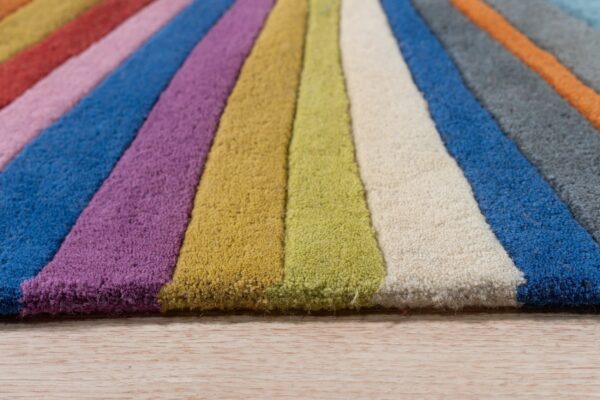 Close-up view of a multicolor striped rug with varying pile heights, resting on light wood flooring.