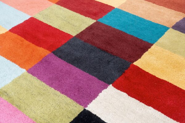 Vibrant multicolored rug featuring a close-up geometric pattern of varied bright rectangular blocks.