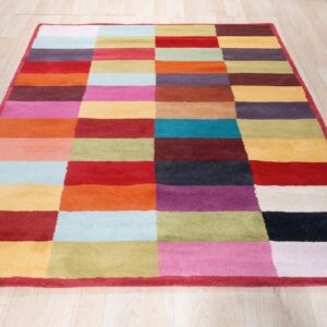 Vibrant geometric rug with staggered multicolored blocks sits on light blonde wood flooring.