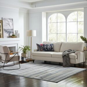 Gray and blue striated rug under a beige sofa on dark wood floors in a bright living room.