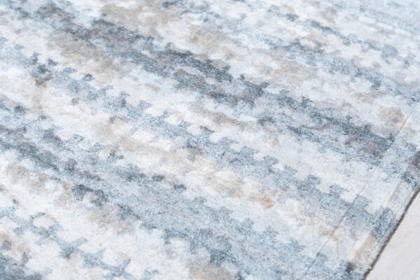 Close-up of a medium-pile rug showing an abstract pattern in white, gray, and light beige.