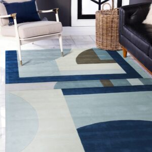 Geometric rug in navy, light blue, beige, and taupe beneath an armchair and black couch.