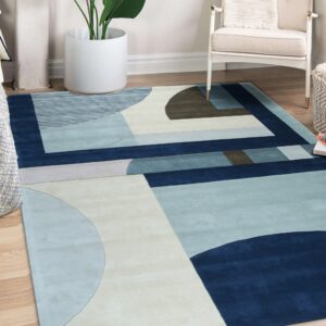 Abstract blue and cream rug with a geometric pattern lies under a white armchair on wood flooring.