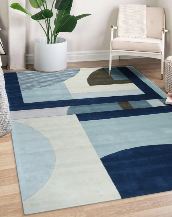 Abstract blue and cream rug with a geometric pattern lies under a white armchair on wood flooring.