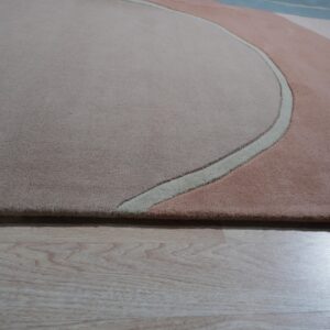 Abstract high-pile rug in blush, taupe, and light blue with carved curved lines on light wood floor.