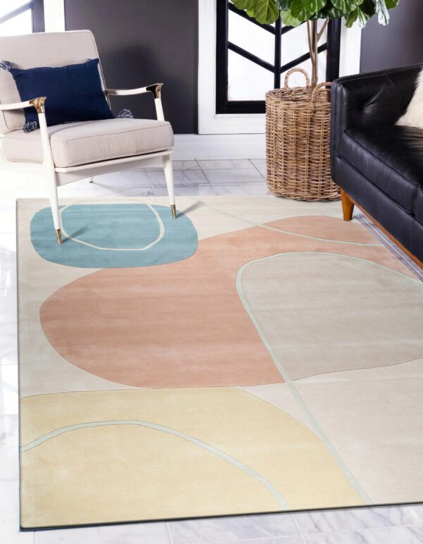 Low pile rug featuring abstract shapes in blue, peach, and yellow beneath a cream armchair.