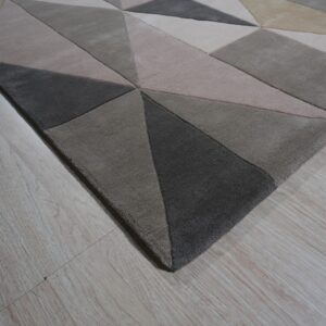 Textured neutral rug with geometric blocks of light beige, taupe, and dark gray on light wood floor.