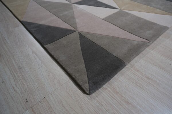 Textured neutral rug with geometric blocks of light beige, taupe, and dark gray on light wood floor.