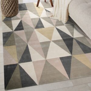 Geometric rug in gray, beige, and blush triangles placed on light plank flooring with neutral furniture.