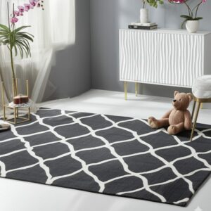 A dark gray rug with a white trellis pattern covers white flooring next to a cabinet and teddy bear.