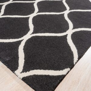 Black, textured rug with bold off-white trellis pattern on a pale wood floor.