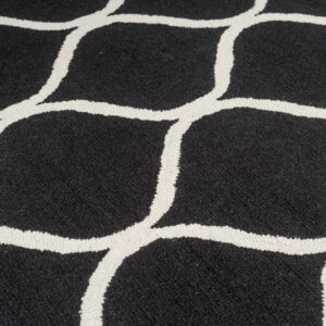 Black rug with a thick, off-white, textured looping geometric pattern in close detail.