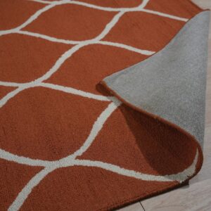 Textured orange rug with a white trellis pattern is partially rolled back on light wood flooring.